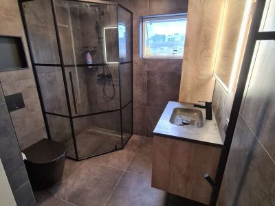 Grijze badkamer met lampen in de spiegel boven de wasbak