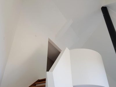 Het strak gestucte trappenhuis op de foto oogt clean en minimalistisch, waardoor de ruimte een eigentijdse uitstraling krijgt.